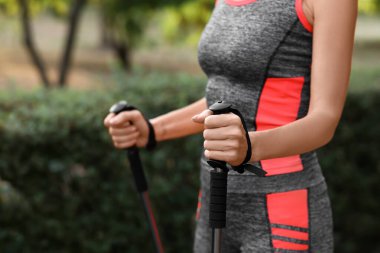 Güzel, olgun bir kadın parkta sırıklarla antrenman yapıyor, yakın plan.