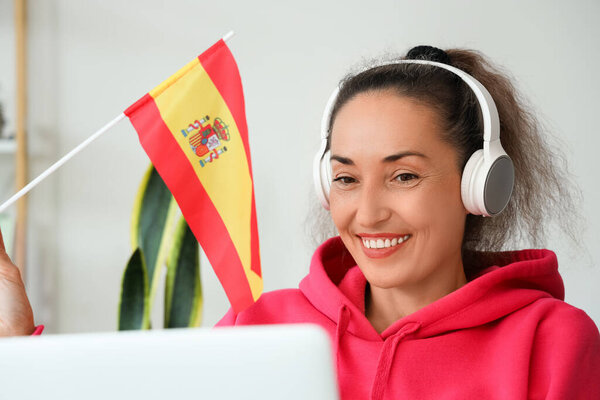 Mature woman with laptop studying Spanish online at home
