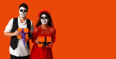 Meksika Ölüler Günü için giyinmiş genç çift (El Dia de Muertos) turuncu arka planda mesaj için yer var