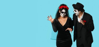 Meksika Ölüler Günü (El Dia de Muertos) için giyinmiş genç çift açık mavi arkaplan ve metin için yer var