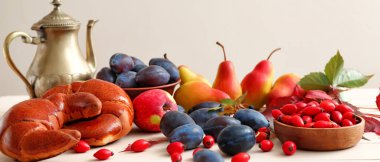 Meyveli güzel sonbahar kompozisyonu, leziz hilal ve beyaz masada çaydanlık.