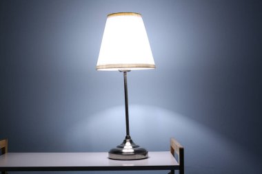 Karanlık odadaki raflarda parlayan lamba.