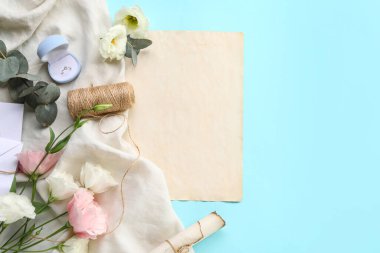 Boş kartlı kompozisyon, nişan yüzüğü ve mavi arka planda güzel östoma çiçekleri.