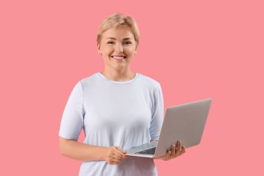 Pembe arka planda dizüstü bilgisayarı olan mutlu genç bayan programcı.