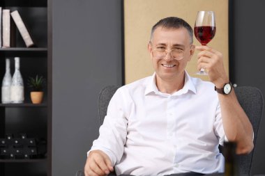 Yetişkin bir adam evde şarap tadıyor.