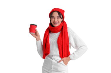 Beyaz arka planda bir fincan sıcak kahveyle sıcak giysiler içinde genç bir kadın.
