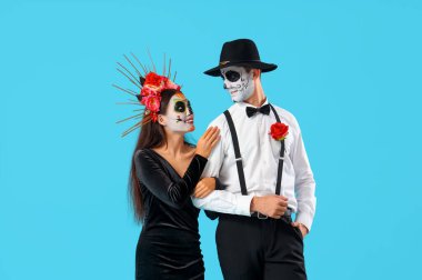 Mavi arka planda Meksika Ölüler Günü (El Dia de Muertos) için giyinmiş genç çift