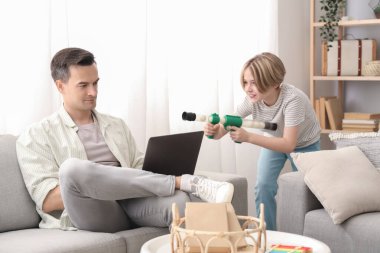 Dizüstü bilgisayarı olan genç bir adam evdeki yaramaz oğlundan dolayı stresli.