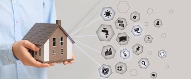Gri arka planda ev modelini tutan kadın. Akıllı Ev kavramı