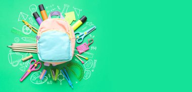 Okul çantası ve yeşil arkaplan üzerine farklı kırtasiye malzemesi.