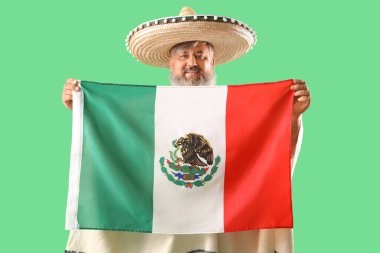 Yeşil arka planda Meksika bayrağı olan şapkalı olgun bir adam.