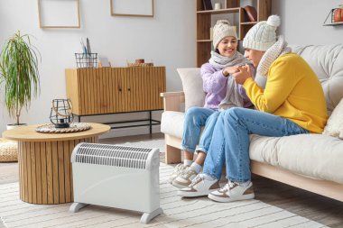 Genç çift kaloriferin yanında ısınıyor.