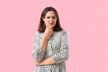 Displeased young woman on pink background clipart