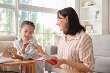 Annesiyle küçük bir kız evdeki domuz kumbarasına para yatırıyor.