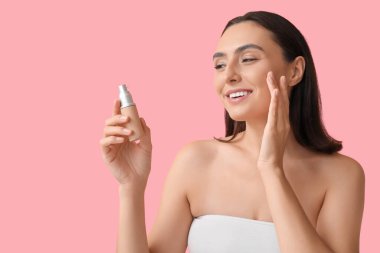 Pembe arka planda makyajlı genç bir kadın, yakın plan.