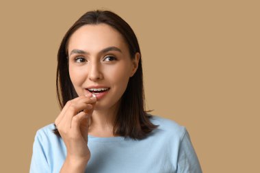 Güzel genç bir kadın kahverengi arka planda hap alıyor.