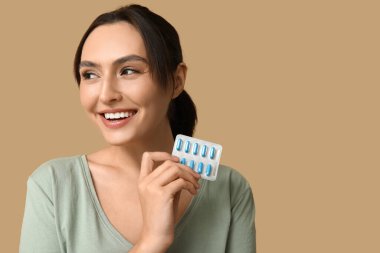 Kahverengi arka planda hapları olan güzel bir kadın.