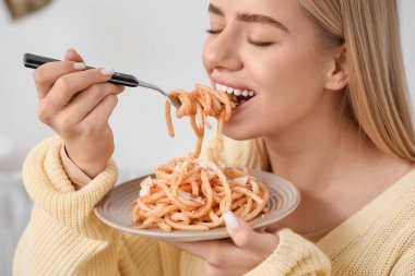 Young woman eating tasty pasta at home, closeup clipart