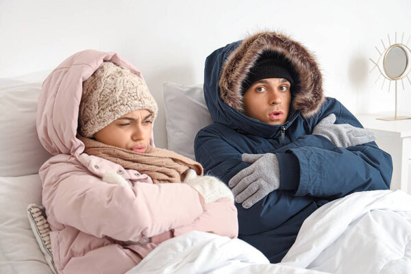 Замороженная молодая пара с пылесосами, лежащими в спальне