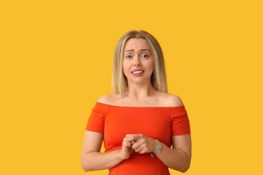 Sarı arka planda utangaç genç bir kadın.