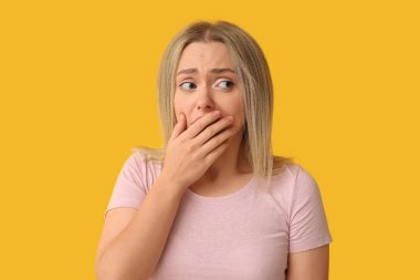 Embarrassed young woman on yellow background clipart