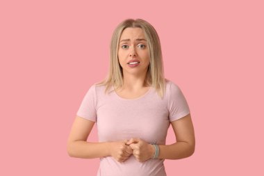 Pembe arka planda utangaç genç bir kadın.