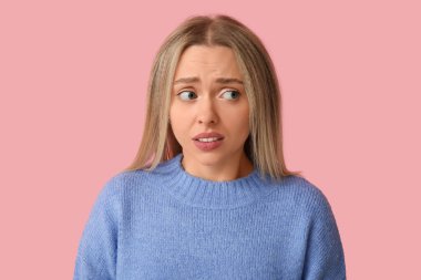 Embarrassed young woman on pink background clipart