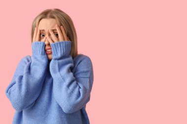 Pembe arka planda utangaç genç bir kadın.