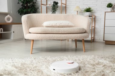 Modern robot süpürgesi oturma odasındaki halıda.
