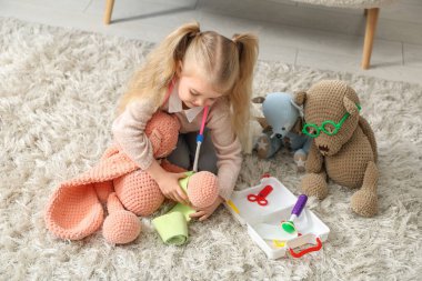 Evde ilk yardım çantası ve oyuncaklarıyla oynayan sevimli küçük kız.