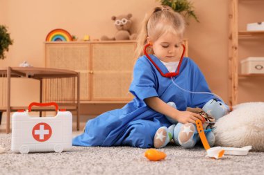 Şirin küçük kız doktor evde yerde oynuyor.