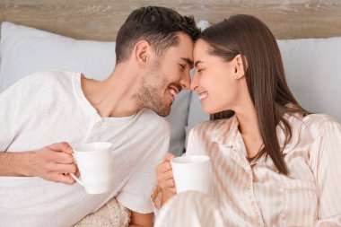 Yatakta kahve içen genç bir çift.