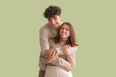 Yeşil arka planda sarılan şık elbiseli güzel bir çift.