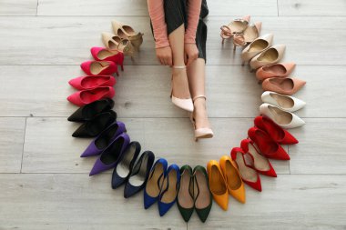 Dişi bacaklar ve beyaz ahşap arka planda birçok modern yüksek topuklar.