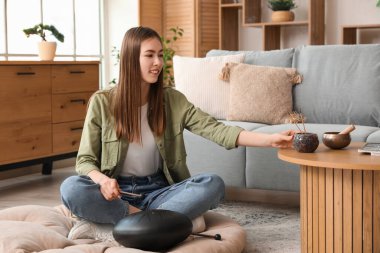 Glukofonlu genç bir kadın masadan aroma çubukları alıyor.