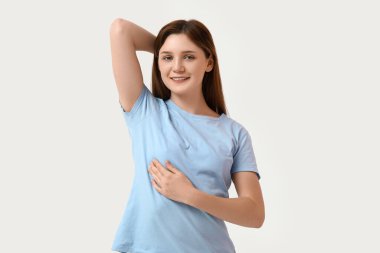 Beyaz arka planda göğüslerini kontrol eden genç bir kadın.