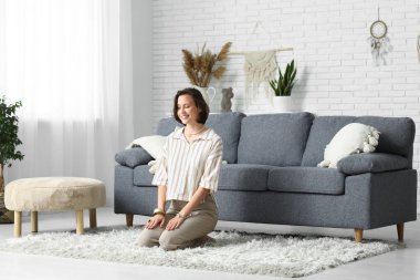 Genç bir kadın evde yerde oturmuş meditasyon yapıyor.