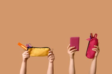 Bej arka planda kırtasiyeli defter ve kalem kılıfları tutan kadın eller