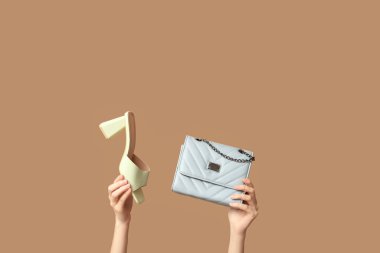 Torbalı kadın elleri ve bej arka planda topuklu sandalet.