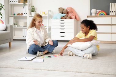 Ofiste yerde plastik kalıplar döşeyen Afro-Amerikalı bir kızla kadın psikolog.