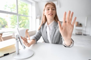 Tablet bilgisayarlı genç iş kadını ofisindeki masada sanal ekran kullanıyor.