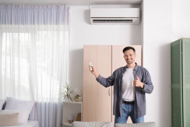 Havalandırma uzaktan kumandalı yakışıklı adam yatak odasında baş parmağını kaldırıyor.