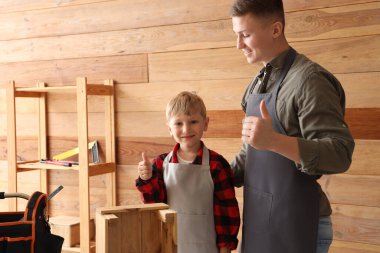 Küçük oğluyla birlikte atölyede başarılı olan erkek işçi.