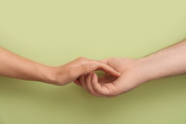 Yeşil arka planda el ele tutuşan sevgi dolu genç çift.