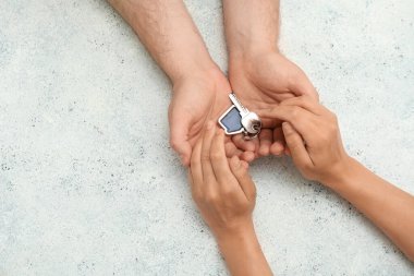 Sevgi dolu genç bir çift ellerinde ıvır zıvırla grunge beyaz arka planda ev şeklinde bir anahtar tutuyorlar.