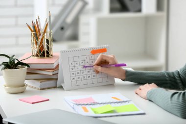 Güzel, genç bir kadın, takvimdeki tarihi işaretliyor, yakın plan.