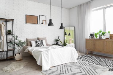 Rahat yatağı, aynası ve lambaları olan modern bir yatak odası.