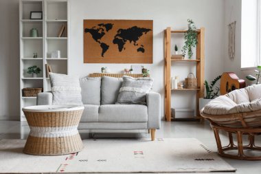 Rahat bir kanepe, masa ve dünya haritası oturma odasının içindeki beyaz duvarda.