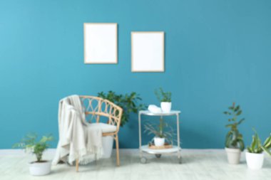 Hasır koltuklu, masalı ve mavi duvarlı farklı evlerden oluşan bulanık bir oturma odası.