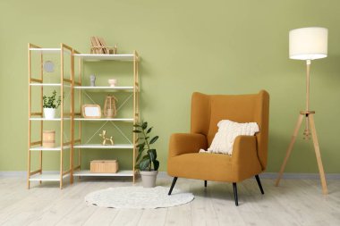 Oturma odasının iç tarafındaki yeşil duvarın yanındaki raf ve rahat koltuk.